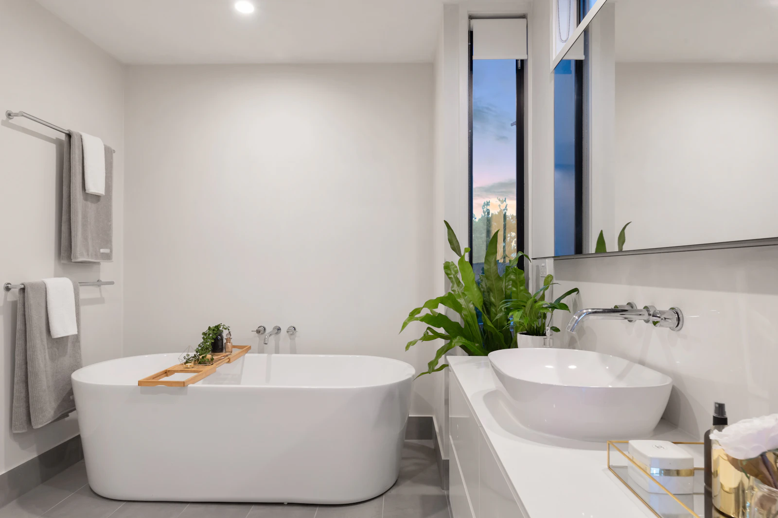 Bright, clean bathroom with a white ceramic bathtub and a potted plant.