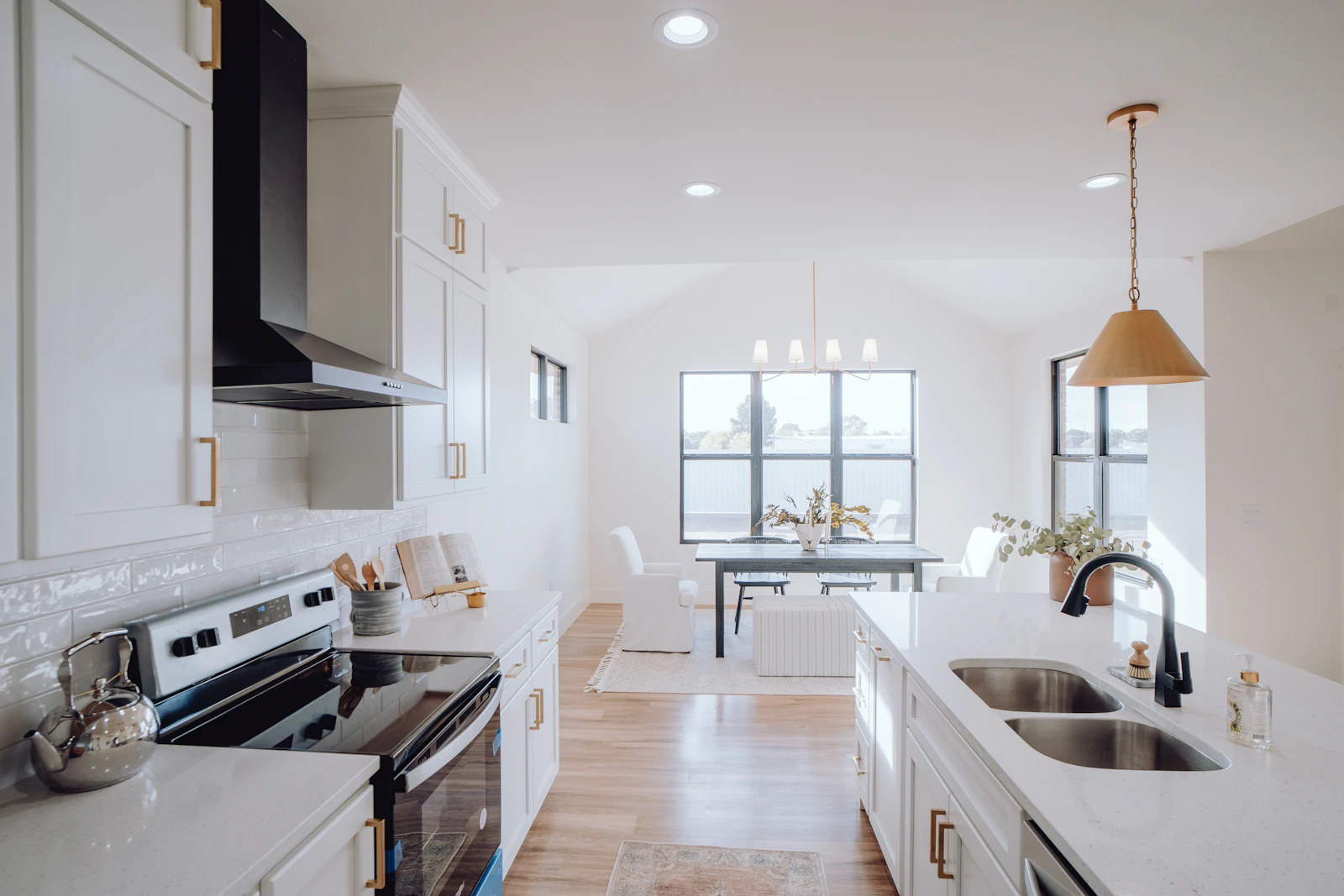 Bright kitchen with sink, stove, and natural light from a window.